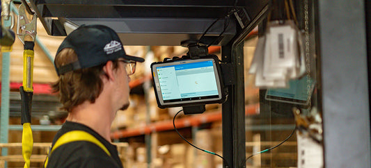 A man is driving a forklift and looking at a Zebra ET40 8" docked in a RAM Mounts docking station