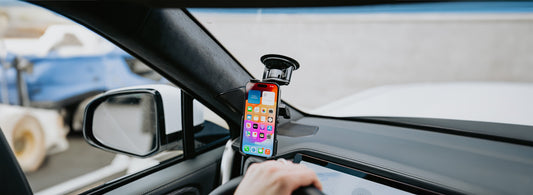 A man using his iPhone 15 that is secured to his Rivian's windshield with the new RAM form-fit holder. 