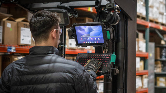 A man is typing on a keyboard mounted to a Tab Active4 Pro in a RAM Mounts Docking Station on a forklift