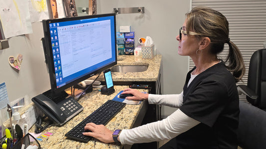 Image of a woman working in an optometry office working on a computer