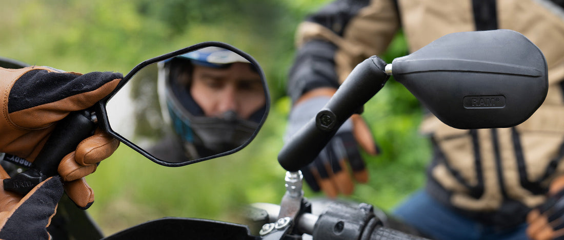 A man is adjusting his motorcycle mirrors, the RAM® Tough-Mirror™