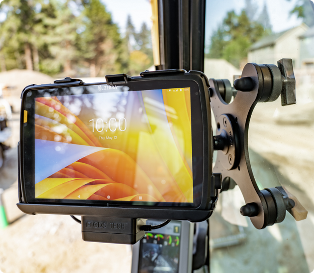 Rugged Zebra tablet displaying colorful lock screen showing 10:00 time secured in RAM® Magnetic holder with magnetic mount attached to vehicle window pillar, providing hands-free access to mobile computing in field operations and outdoor work environments.