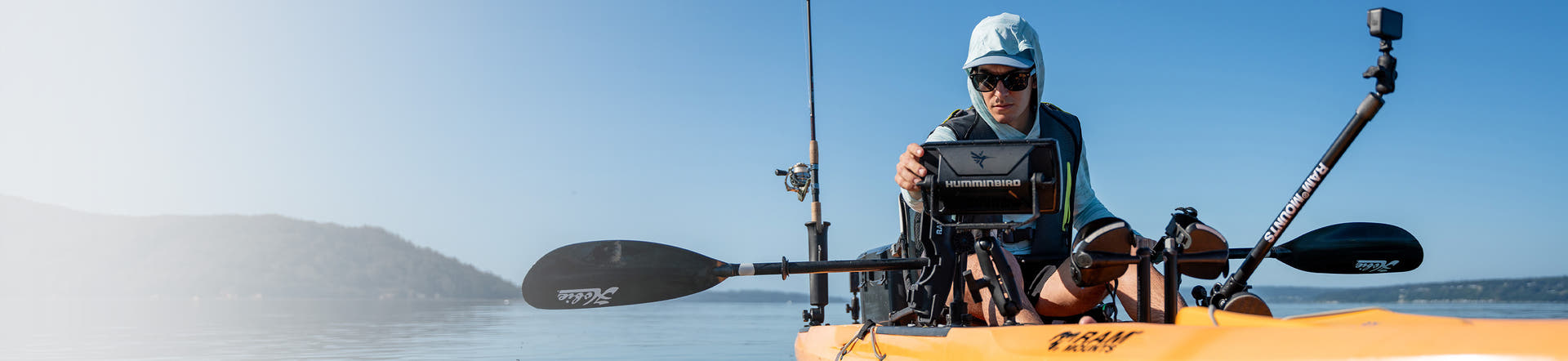 Homepage banner featuring RAM fishing mounts and accessories including a rod holder, fish finder mount, and action camera mount being used on a yellow kayak.