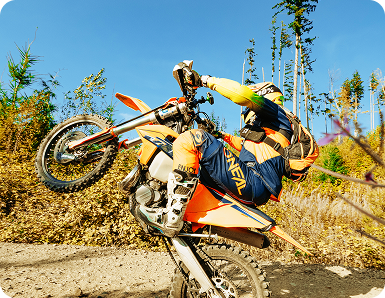 Person performing wheelie on an orange dirt bike