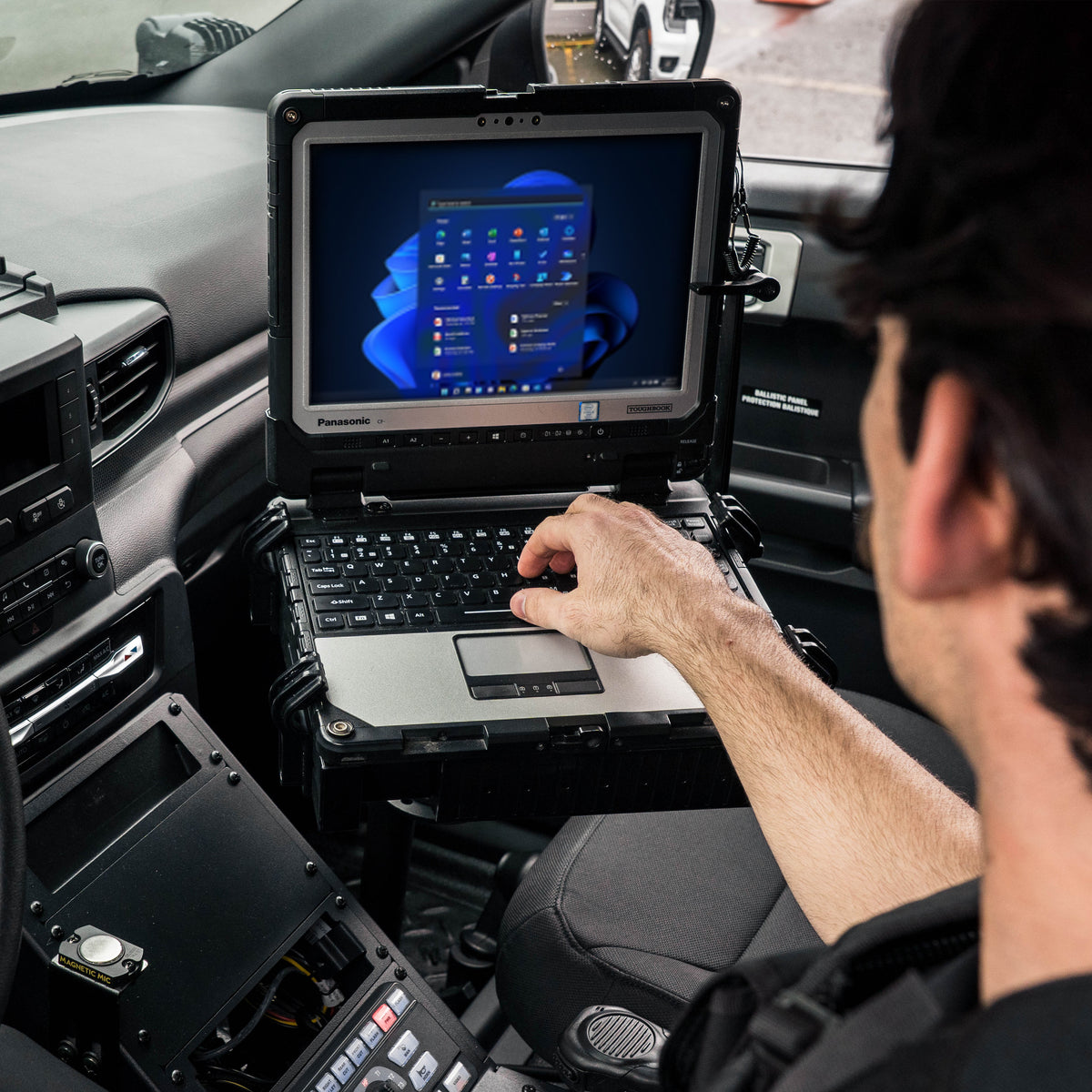 Police vehicle laptop mounted beside the center console for secure in-vehicle computer access