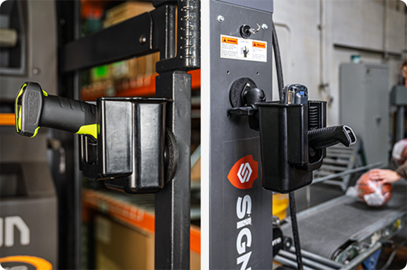Industrial barcode scanner and handheld devices mounted in RAM® Magnetic holders attached to warehouse equipment and metal shelving, providing convenient tool storage and quick access during inventory management and logistics operations.