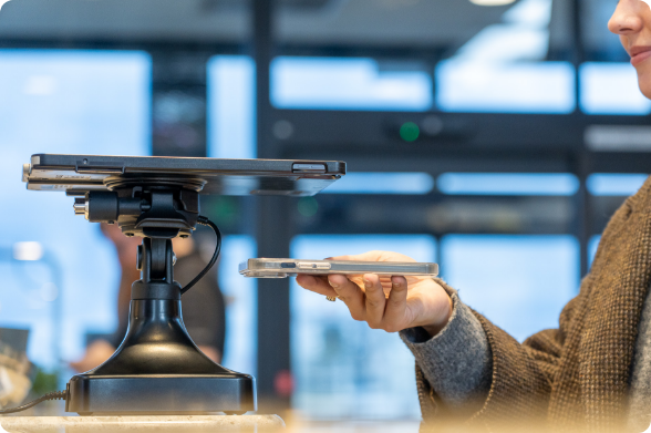 Airline passenger scanning smartphone ticket with a GDS® Kiosk dock, demonstrating easy device docking and undocking during pre-boarding procedures.