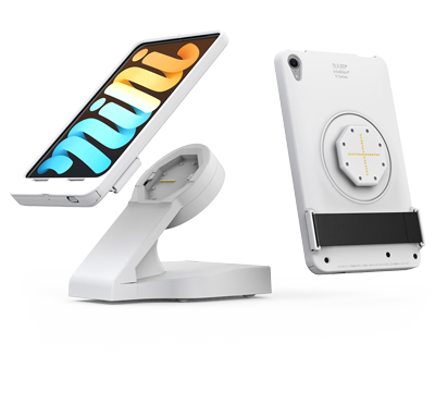 White iPad mini tablet mounted on an IntelliSkin H Series desktop docking station with magnetic alignment and integrated charging. The image shows both the front and rear views of the tablet, highlighting the circular magnetic docking interface and charging contacts on the back. The tablet is displayed at an angled viewing position on a sleek white stand designed for point-of-sale, kiosk, retail, hospitality, and workstation applications. White background.
