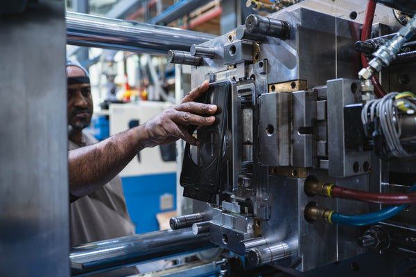 Person removing part from plastic injection molding machine