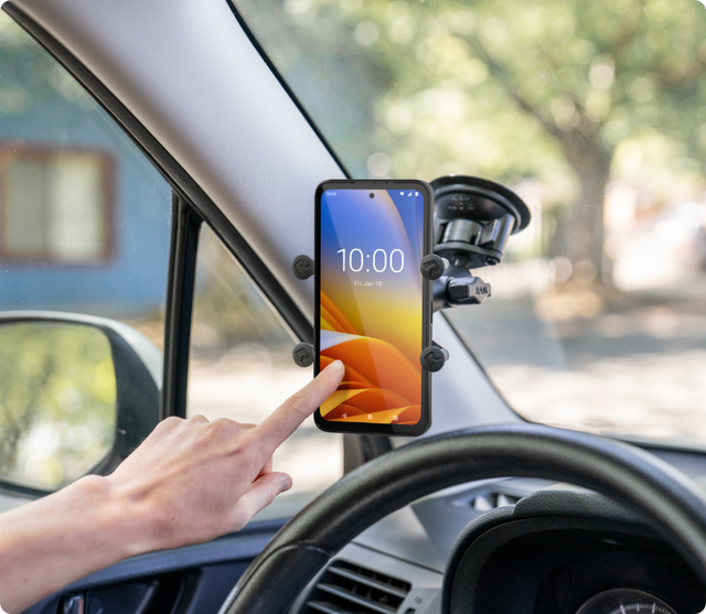 Close-up image of a person tapping the screen of a Zebra EM45 in a RAM X-Grip suction cup mount to the inside windshield of a car