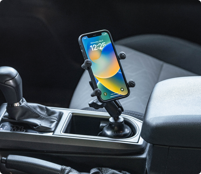 iPhone displaying colorful gradient lock screen showing 12:25 time secured in RAM® X-Grip® holder mounted in vehicle cup holder, demonstrating convenient smartphone positioning for hands-free access while driving.