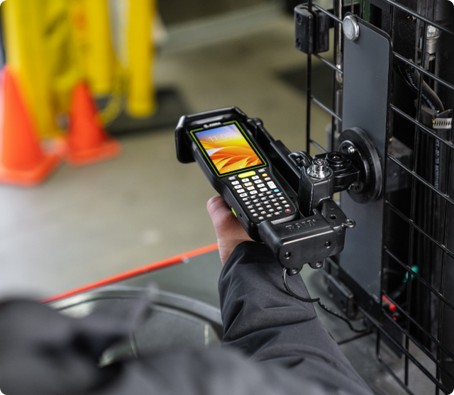 Image of a man inserting a MC3400 Mobile Computer into the form-fitting design of RAM docks for MC3400 and MC3300 on a forklift